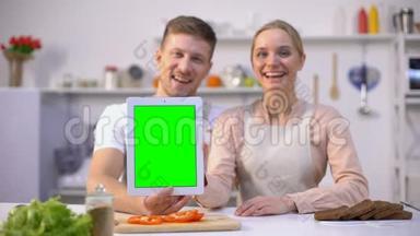 双手拿着绿色屏幕的平板电脑，竖起大拇指，美味的食谱应用程序